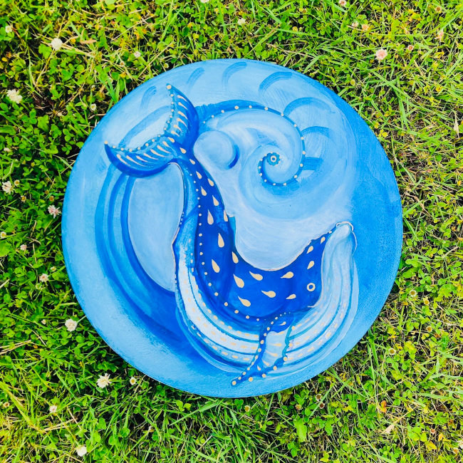 Circular blue painting of a blue whale in the sea 