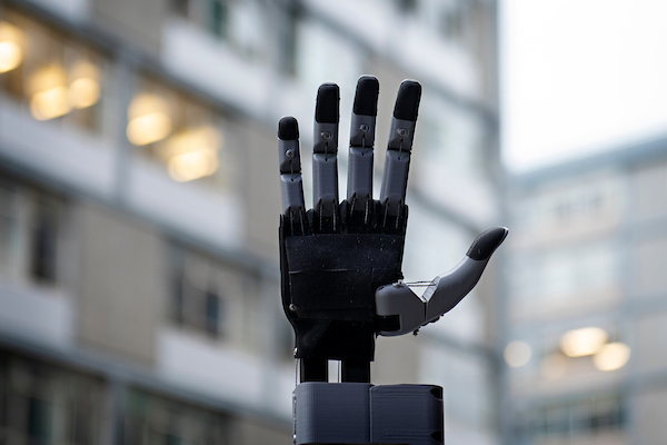 Metacarpal designed prosthetic hand with joints extended and palm open. Buildings out of focus in the background.