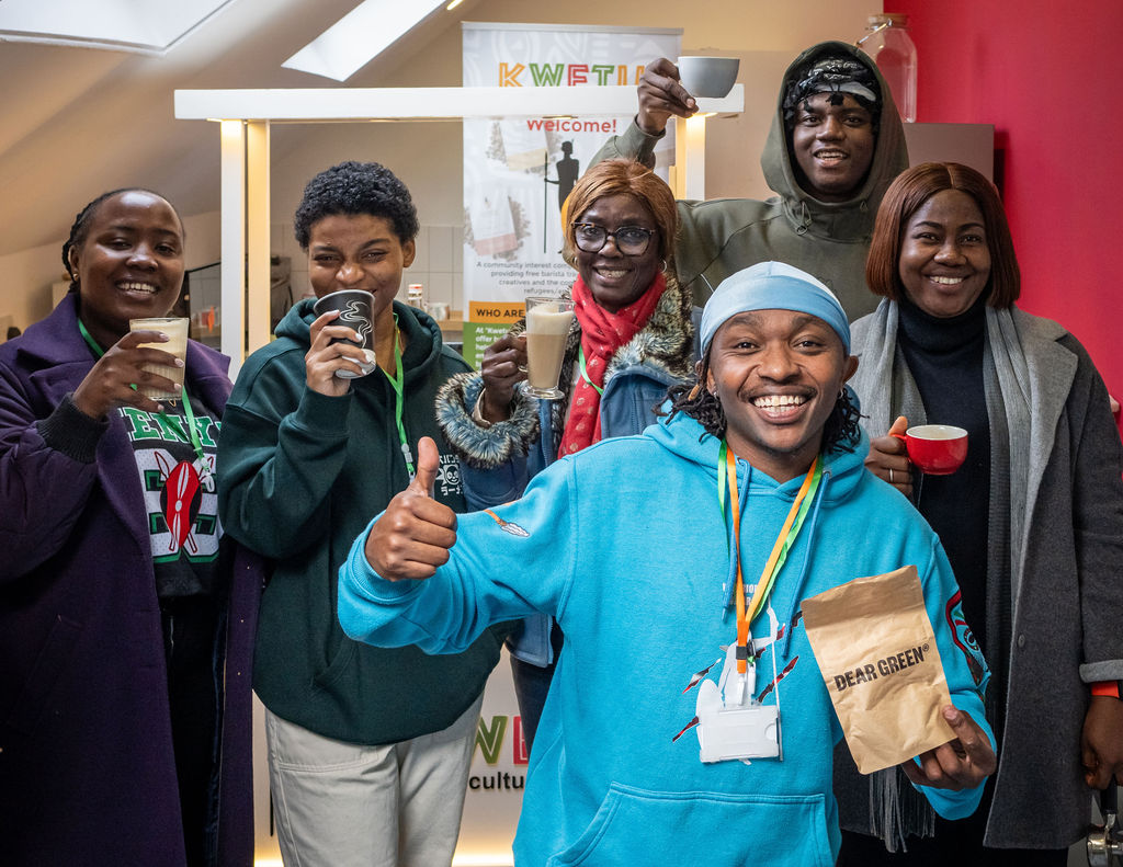 Antony from Kwetu coffee with workshop attendees. He is holding a bag of coffee and smiling at the camera.