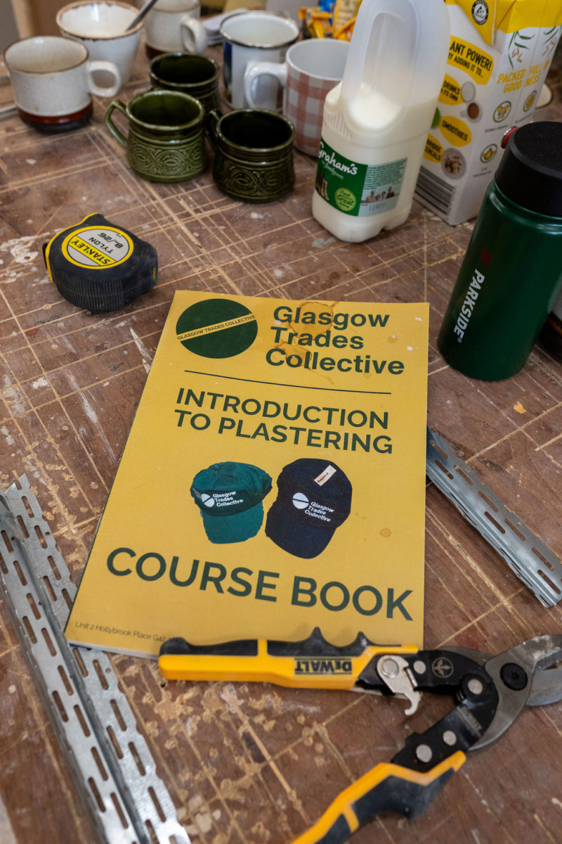 Image of Glasgow Trades Collective's Introduction to Plastering Course Book on a work table surrounded by tools