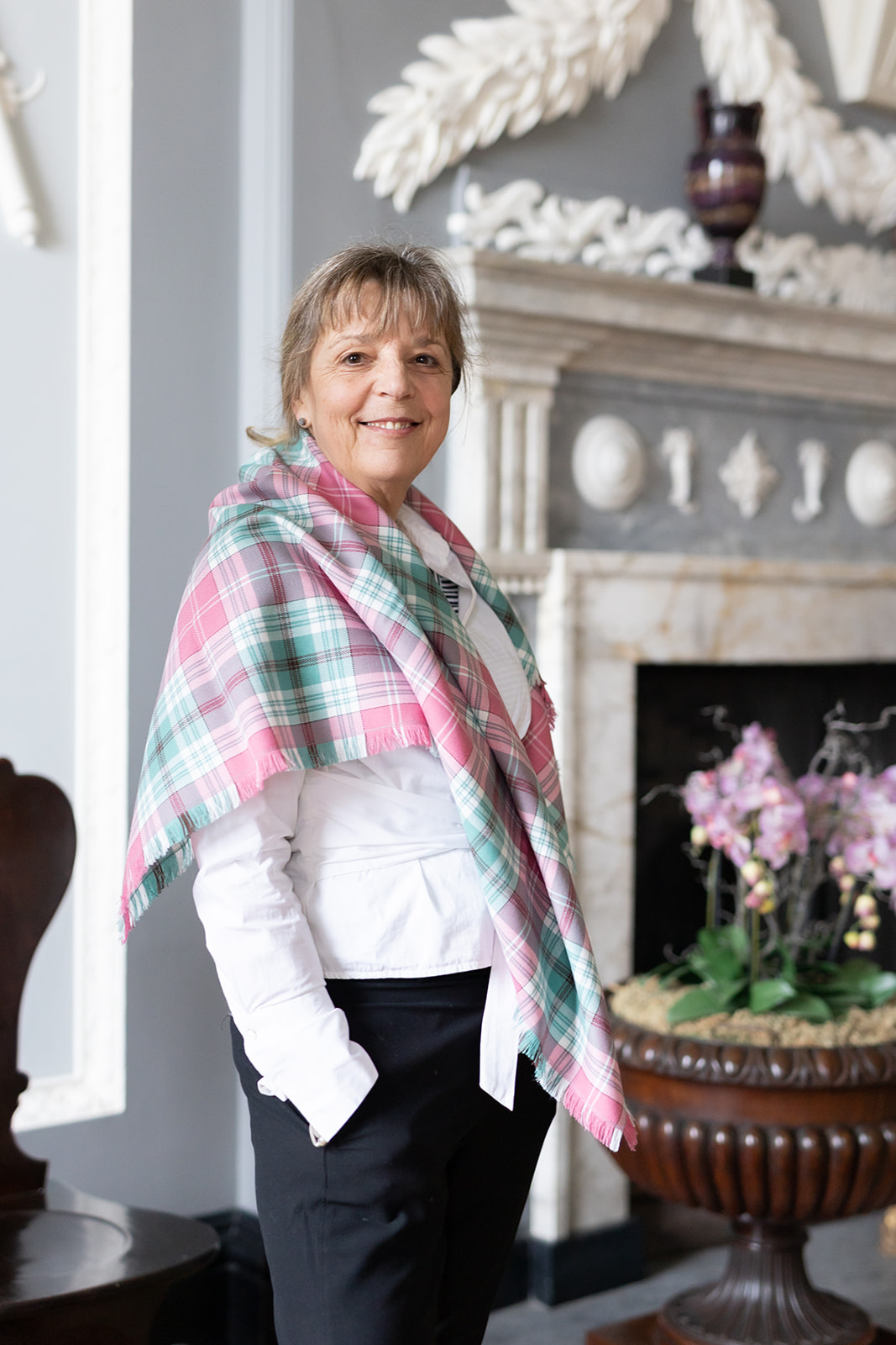 Image of person looking at the camera draped in white, pink and green tartan fabric