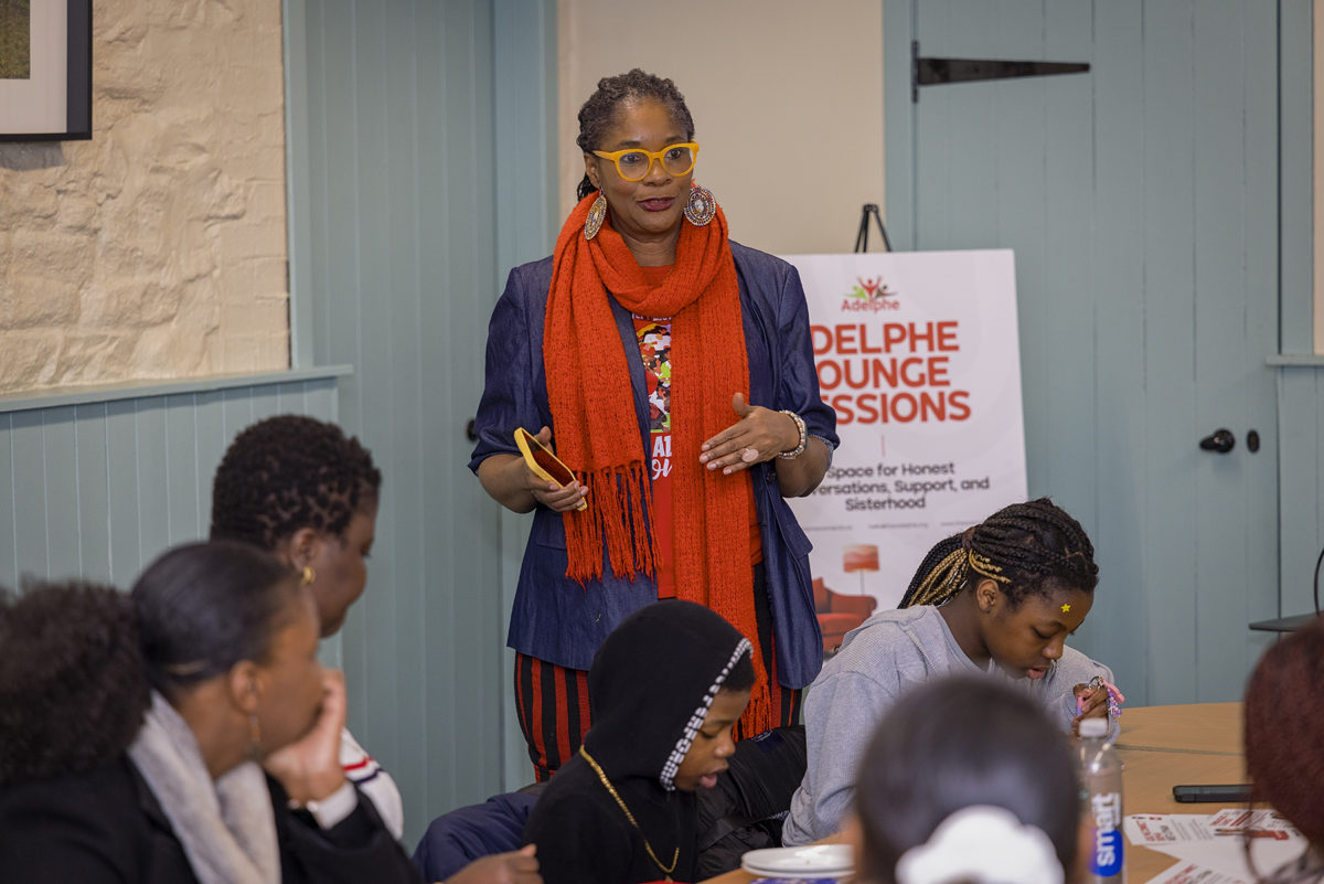 A woman stands and speaks in front of a group of people at an Adelphe Connect event.