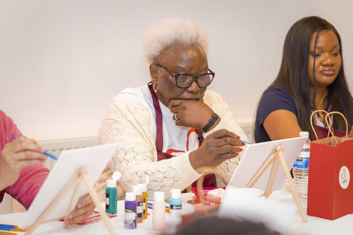 A person concentrates while they paint at an Adelphe Connect event.