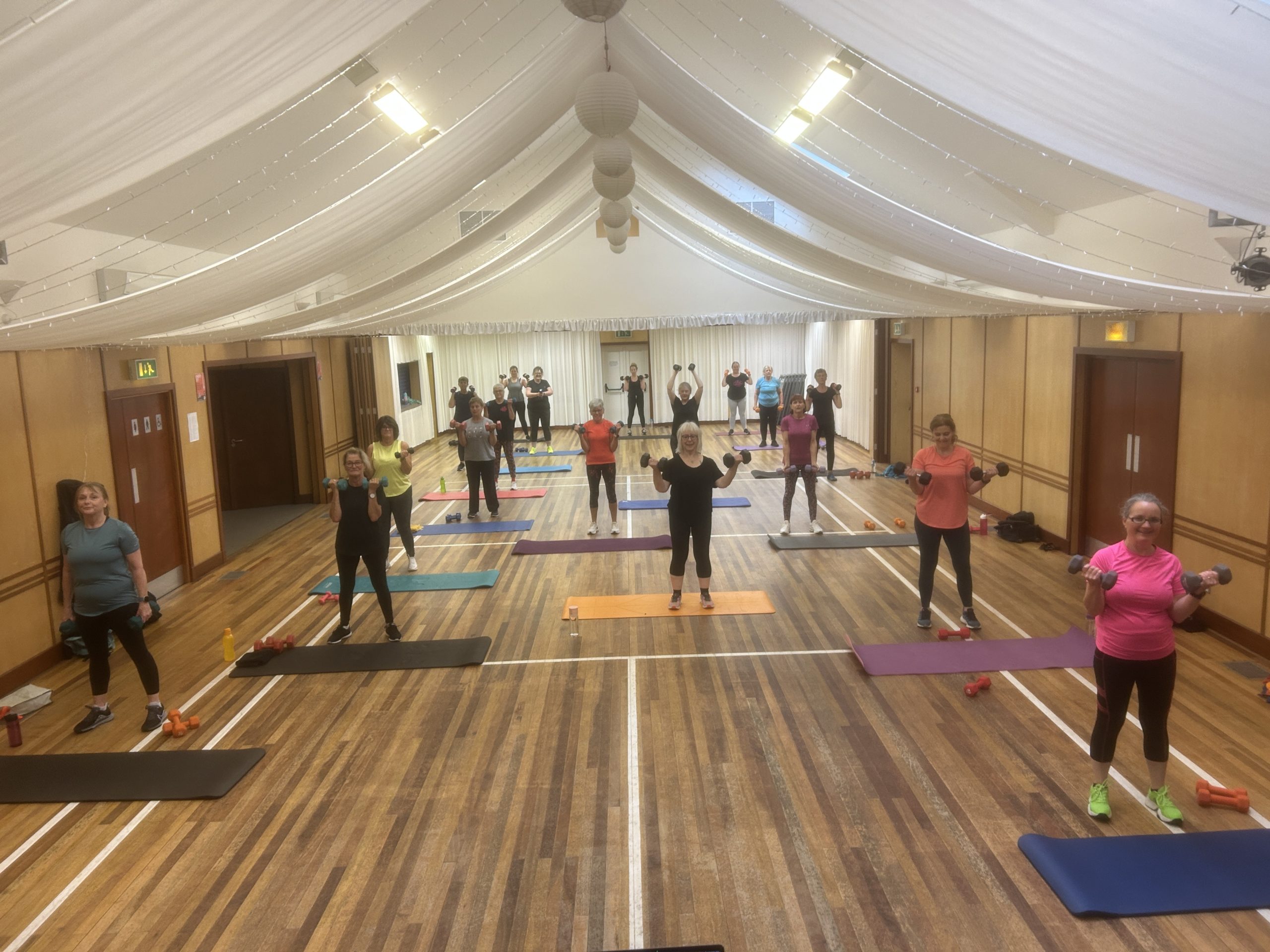 People working out with yoga mats and weights at an Orkney Dance & Fitness class